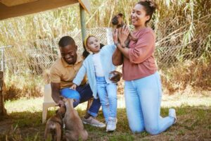 Casal e filha brincando com filhotinhos de cães que estão para adoção